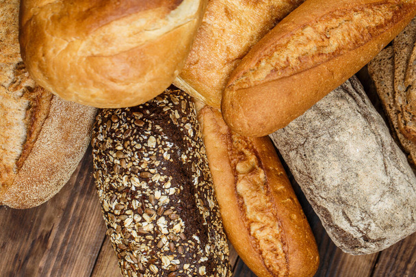 Diferentes panes y panecillos con trigo y harina sobre una mesa de madera
 - Foto, Imagen
