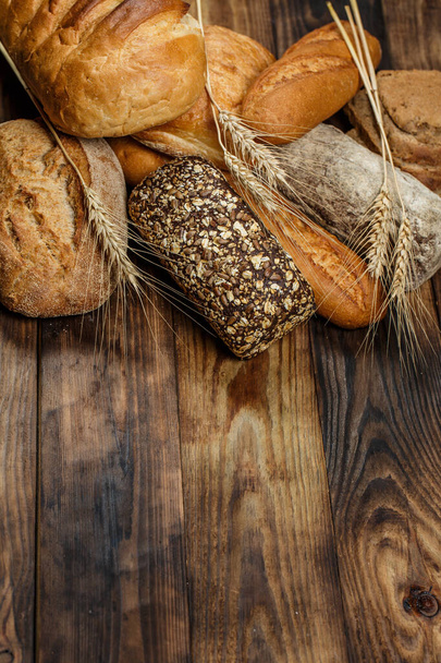 Різні хліби хліба і рулони з пшеницею і борошном на дерев'яному столі
 - Фото, зображення
