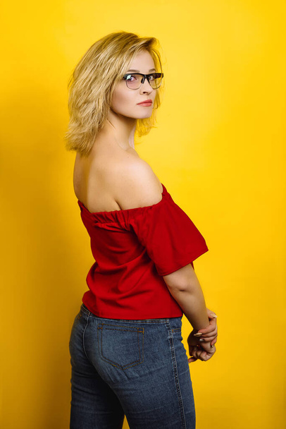 emotional girl posing on a yellow background. blonde in a red top. young woman in glasses is surprised - Photo, Image
