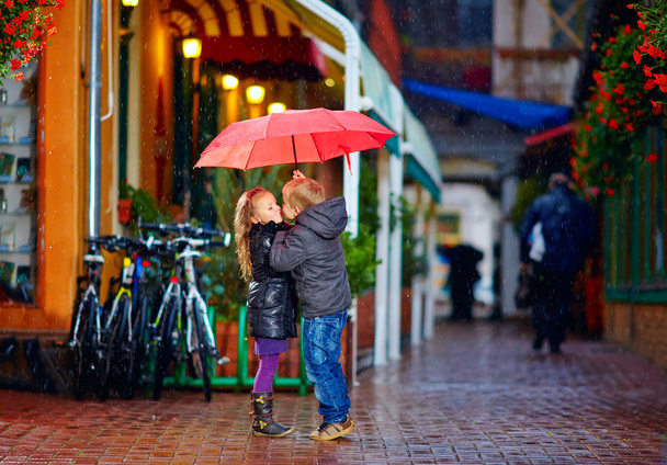 young couple kissing under the umbrella on the street - Φωτογραφία, εικόνα