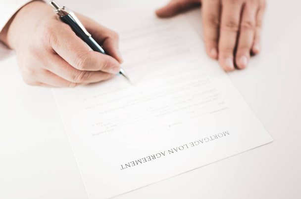 Gros plan d'un homme d'affaires signant un contrat de prêt hypothécaire avec un stylo
. - Photo, image