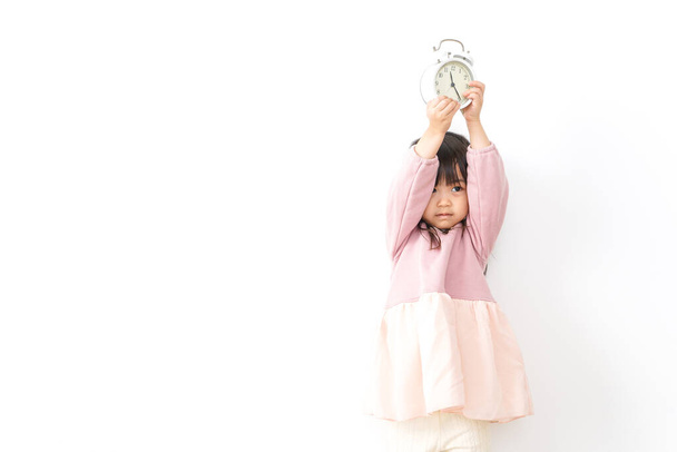 little girl holding alarm clock - 写真・画像