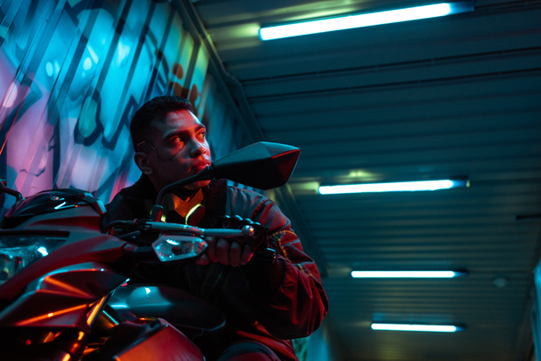 low angle view of mixed race cyberpunk player on motorcycle  - Fotoğraf, Görsel