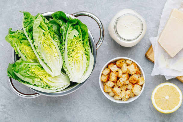 Ingrediënten voor klassieke Caesar salade met Romaine sla, zelfgemaakte dressing, Parmezaanse kaas en knapperige croutons. Bovenaanzicht, kopieer ruimte. - Foto, afbeelding