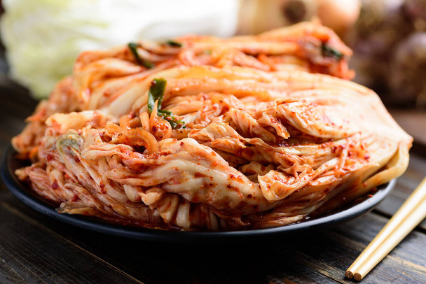 Kimchi káposzta tányéron evőpálcikával a fa asztalon, koreai étel - Fotó, kép