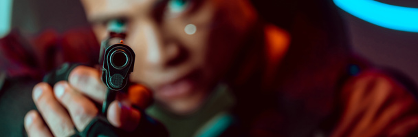 coup panoramique de pistolet dans les mains du joueur cyberpunk bi-racial
  - Photo, image