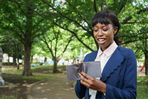 młoda afrykańska bizneswoman trzyma portfel w parku - Zdjęcie, obraz