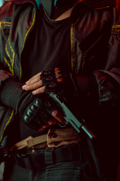 cropped view of armed cyberpunk player in gloves holding gun  - Фото, изображение