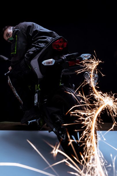 enfoque selectivo de la raza mixta jugador cyberpunk en la máscara de conducción de la motocicleta con chispas en blanco y negro
  - Foto, Imagen