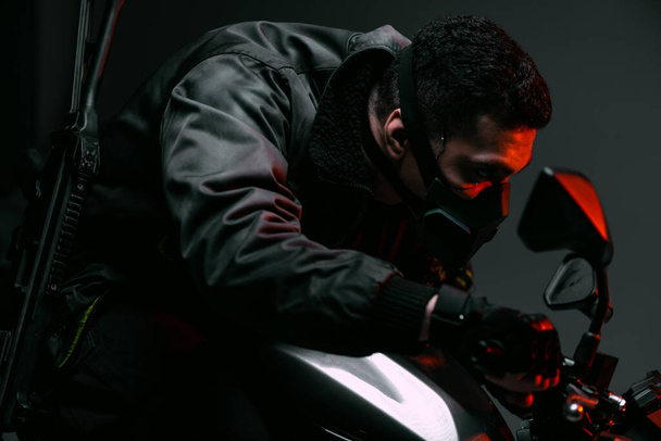 selektivní zaměření nebezpečné smíšené rasy cyberpunk hráč v masce na koni motocykl na šedé  - Fotografie, Obrázek