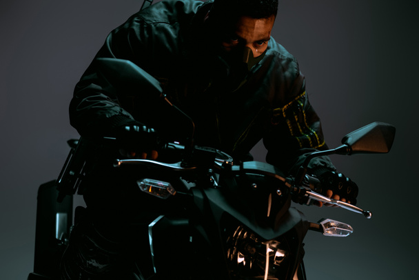 jugador cyberpunk de raza mixta en la máscara de conducción de motocicleta en gris
  - Foto, Imagen