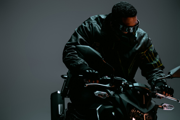jugador cyberpunk de raza mixta en máscara y gafas futuristas a caballo motocicleta en gris
  - Foto, imagen