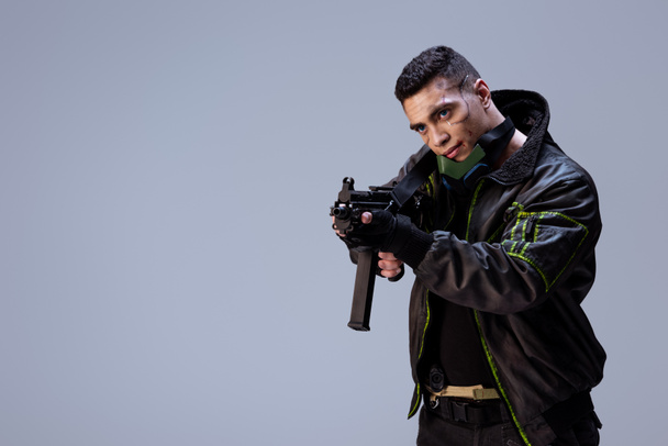 bello bi-razziale giocatore cyberpunk in possesso di pistola isolata su grigio
   - Foto, immagini