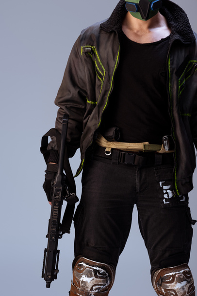 rajattu näkymä cyberpunk pelaaja naamio tilalla ase seistessä eristetty harmaa
   - Valokuva, kuva
