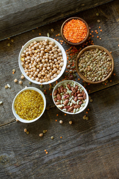 食事と健康的な食事の概念、ビーガンタンパク源。マメ科植物(ひよこ豆、赤レンズ豆、カナダのレンズ豆、豆、ブルグル)の生。平らなレイアウトの上からの眺め。スペースのコピー. - 写真・画像