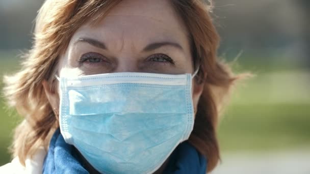 Nervous woman wearing a protective mask against covid-19 outside in spring              Astonishing portrait of a frightened woman in a sanitary mask against dangerous covid-19 trying to fight against the epidemic in a park on a sunny day in spring.  - Filmagem, Vídeo