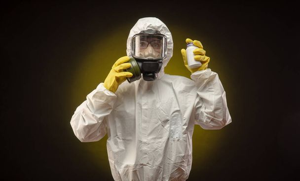 コロナウイルスの薬を入れたガスマスクをした生物保護服を着た男 - 写真・画像