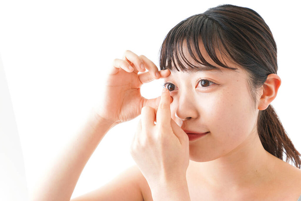 Porträt einer jungen asiatischen Frau mit Augenlinsen isoliert auf weißem Hintergrund - Foto, Bild
