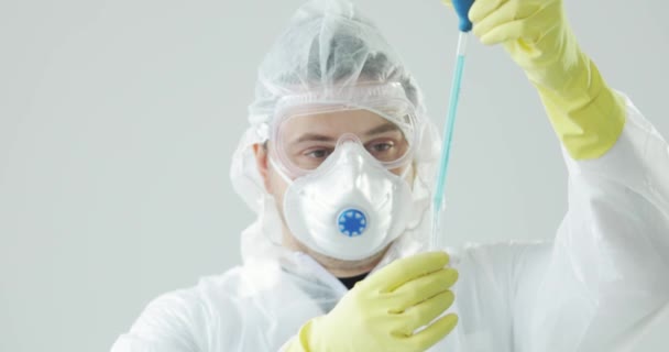 Doctor drips blue solution from pipette into glass tube, coronavirus pandemic. - Filmagem, Vídeo