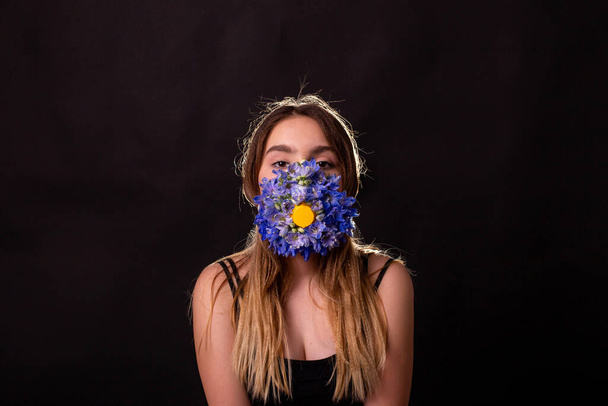 Teenager-Mädchen setzt sich eine Maske aus Blumen auf, um sich vor dem Virus zu schützen - Foto, Bild