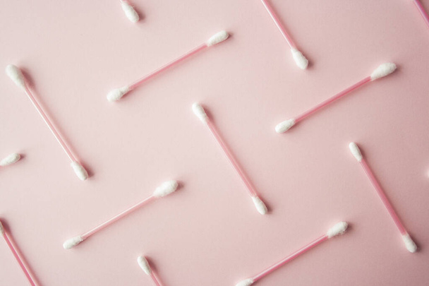 Flat lay cotton buds on pink warm background. Pattern of cotton swubs, beauty and health care concept. Cotton composition - Photo, image