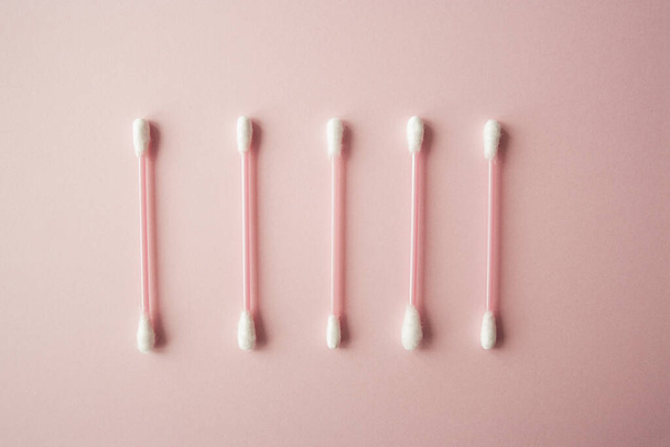Flat lay cotton buds on pink warm background. Row of cotton swubs, beauty and health care concept. Cotton composition - Foto, immagini