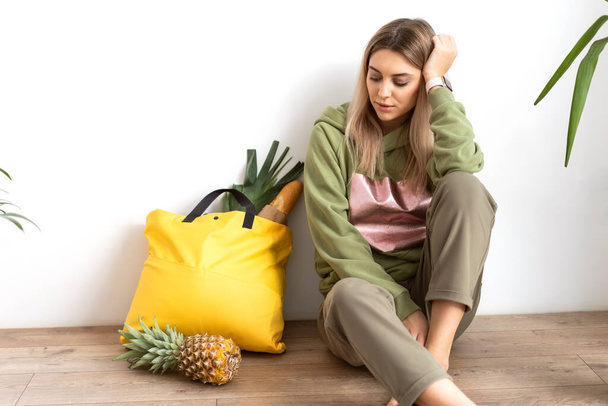 Beautiful fashion girl does shopping with herself, food delivery, take away food.  Girl sitting at home with a bag of food - Фото, изображение