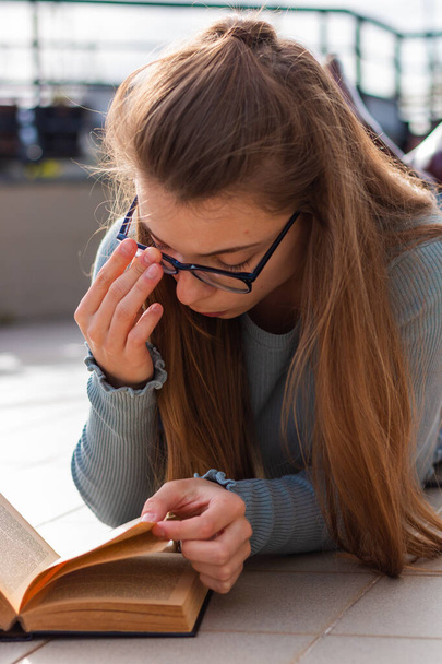 girl with long hair and glasses reading a book - Foto, afbeelding