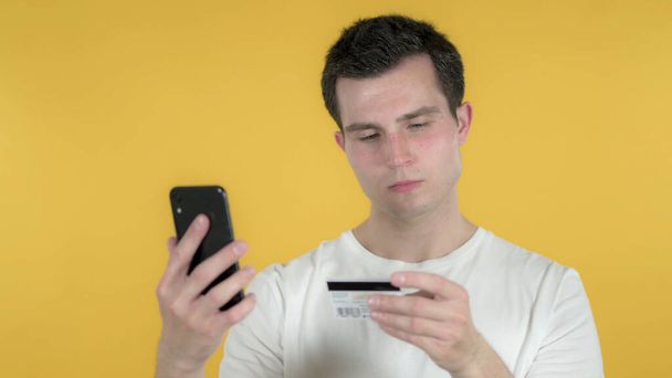 Compras en línea por el hombre casual a través de Smartphone aislado en el fondo amarillo
 - Foto, Imagen