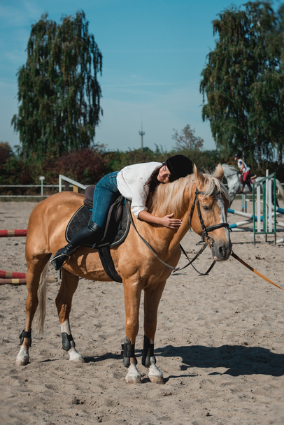Ritratto di giovane donna bruna in camicia bianca e casco su un cavallo. impara a cavalcare. lezioni di equitazione su un cavallo epodrom
 - Foto, immagini
