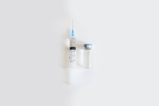 Mavi kapaklı ilaç şişesinin üst görüntüsü ve gri arka planda temiz sıvı ve şırınga. Coronavirus aşısı geliştirme. 2019 nCoV sıvı ilaç, virüs panzehiri. Uzayı kopyala Sağlık hizmeti kavramı - Fotoğraf, Görsel