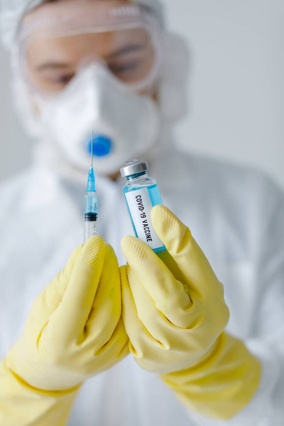 Portrait of doctor in protective clothes fills syringe with coronavirus vaccine. - Photo, Image
