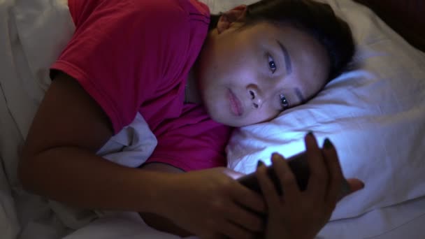 Asian woman play smartphone in the bed at nighttime - Felvétel, videó