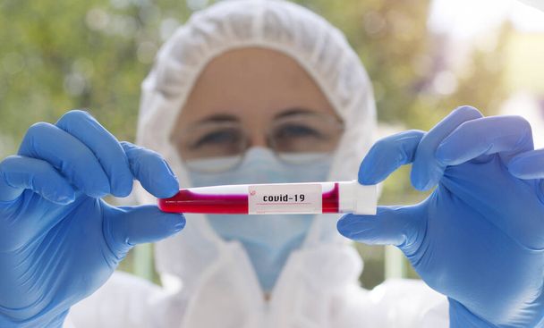  Coronavirus covid 19 flacon de sang infecté en main du médecin féminin avec masque chirurgical et lueur. Coronavirus covid 19 laboratoire de recherche, recherche sur le vaccin coronavirus covid-19. - Photo, image