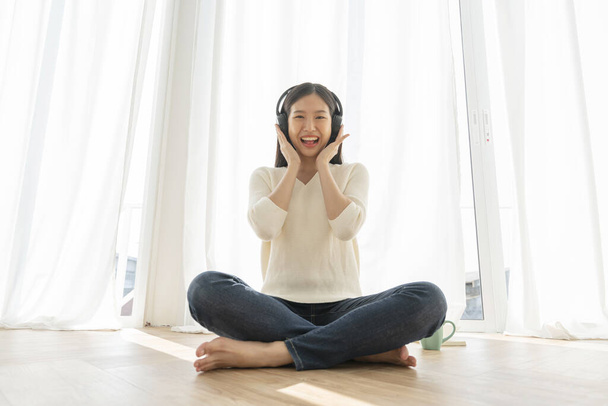 relex and peaceful asian woman enjoy weekend with music headphone morning sunlight near window home background - Photo, image
