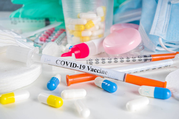Worldwide coronavirus epidemic concept. Pandemic COVID-19, 2019-nCoV. Testing of coronavirus vaccine. Syringe with covid-19 vaccine, against the background of drugs, pills and medical supplies - Photo, image