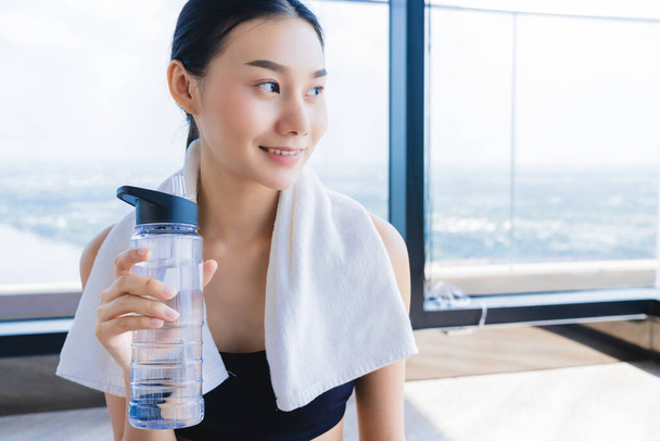 asian healthy aport woman relaxing in gym after workout hand hold pure water drink and white towel - Valokuva, kuva
