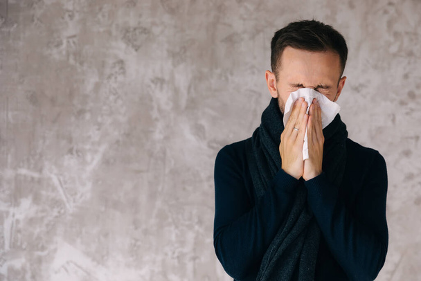 Sick man wearing scarf, blowing nose and sneeze into tissue. Male have flu, virus or allergy respiratory. Healthy, medicine and people concept. Headache and fever remedies. - Foto, imagen