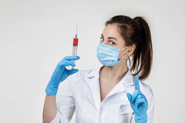 woman doctor in mask and rubber gloves holding syringe - Фото, изображение