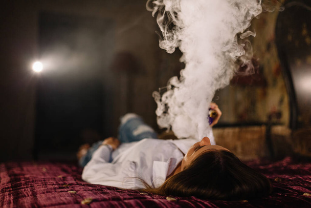 Chica fumando en la cama
. - Foto, Imagen