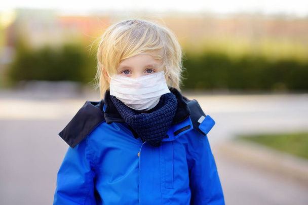 Little boy wearing a protective mask in airport, supermarket or other public place. Safety during COVID-19 outbreak. Epidemic of virus covid. - 写真・画像