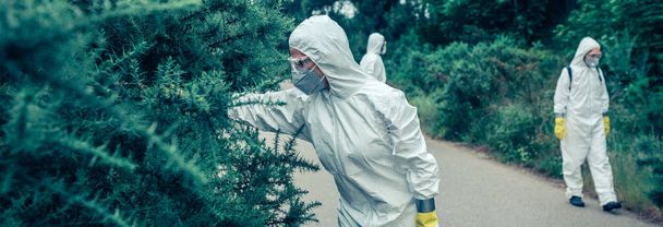 Bakteriyolojik koruma giysileri giyen insanlar boş yollarda örnekler arıyorlar. - Fotoğraf, Görsel