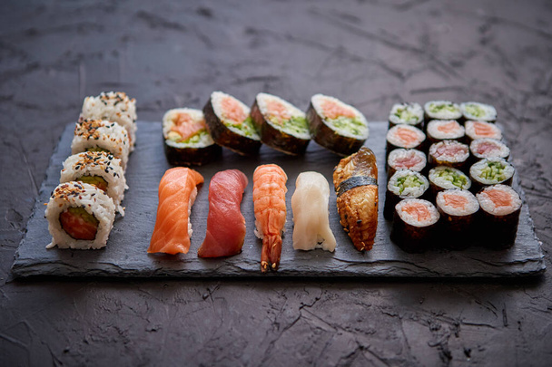 Set de rollos de sushi con salmón y atún servido en tablero de piedra negra - Foto, Imagen