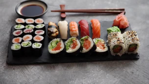 Σύνθεση των διαφορετικών ειδών sushi ρολά τοποθετημένα στο μαύρο του σκάφους πέτρα - Πλάνα, βίντεο
