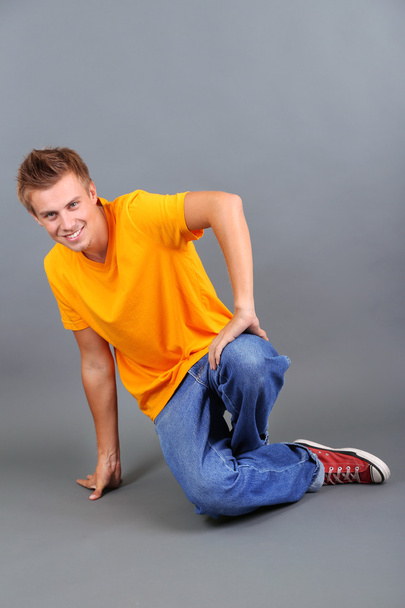 Handsome young man dancing on grey background - Фото, изображение