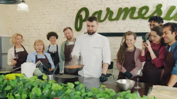Professionele kok bakken voedsel onderwijs stagiaires terwijl studenten klappen handen - Video