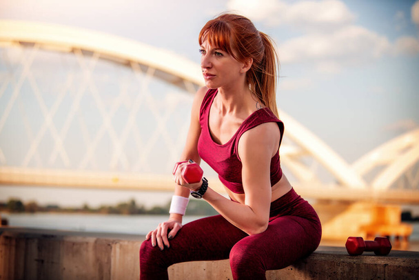 Молодая женщина делает фитнес деятельность и тренировки с гантелями, outside.Fitness, спорт и здоровый образ жизни
. - Фото, изображение