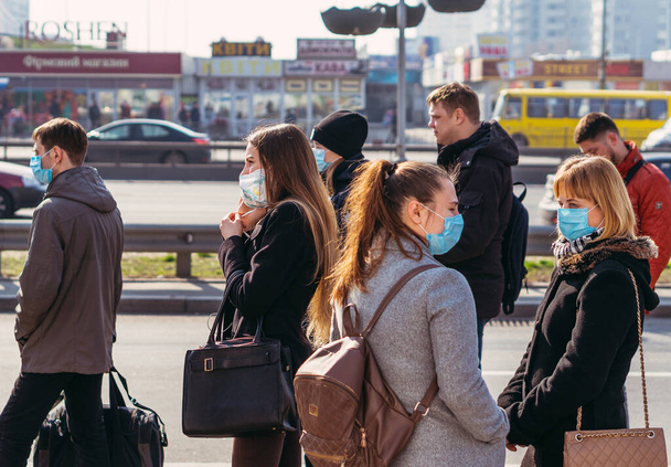 KYIV, UCRANIA 19 de marzo. 2020. Cuarentena en la ciudad de Kiev debido al virus COVID-19. La gente está parada en las paradas de transporte público con máscaras protectoras contra el virus
. - Foto, imagen