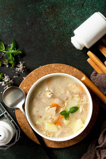 Η έννοια ενός υγιεινού και διαίτης φαγητού, νόστιμη σούπα με κοτόπουλο, τυρί κρέμα και δημητριακά σε ένα σκούρο πέτρινο τραπέζι. Πάνω άποψη επίπεδη lay φόντο. Αντιγραφή χώρου - Φωτογραφία, εικόνα