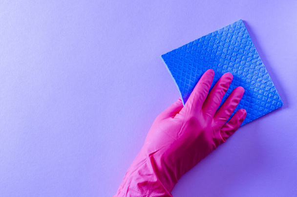 Blue house cleaning sponge in hand in pink rubber glove on pink background. Commercial cleaning company concept - Photo, image